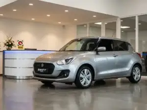 Suzuki Swift tentoongesteld in een moderne autoshowroom met BOVAG-certificering, glanzende betonvloer en sfeervolle spots.