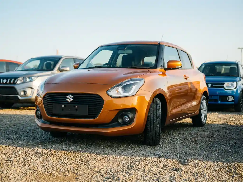 Suzuki Swift op een zonnig occasion-terrein, met twee wazige Suzuki's op de achtergrond en gouden middaglicht op de carrosserie.